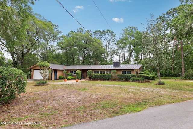 single story home with driveway, an attached garage, a front yard, a standing seam roof, and metal roof