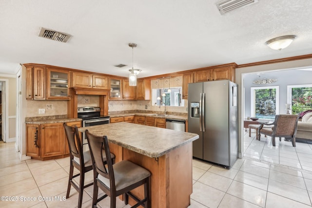 kitchen featuring light tile patterned floors, visible vents, brown cabinets, and appliances with stainless steel finishes