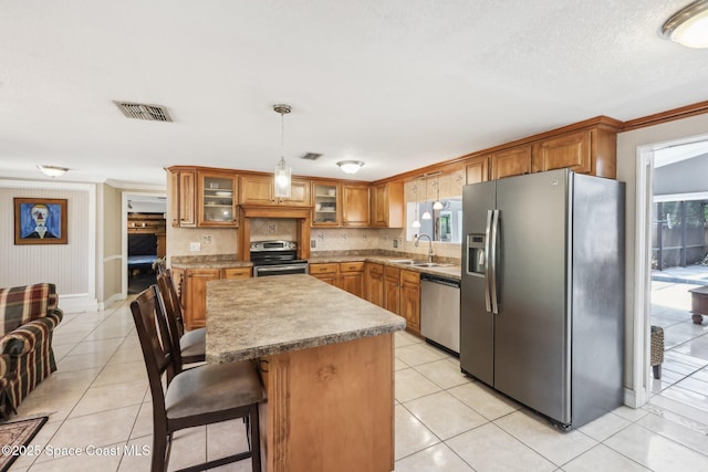 kitchen featuring light tile patterned floors, visible vents, a sink, stainless steel appliances, and brown cabinets