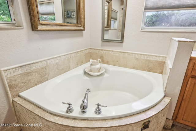 bathroom with a garden tub and a textured wall