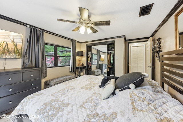 bedroom featuring crown molding, two closets, a ceiling fan, and visible vents
