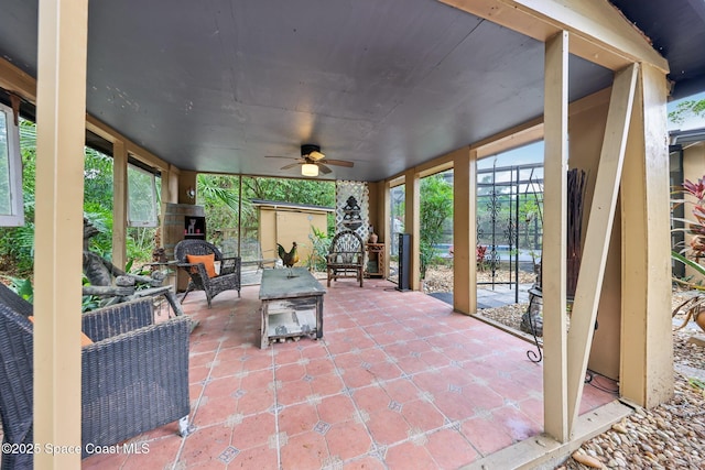 view of patio with an outdoor structure, glass enclosure, a ceiling fan, and an outdoor hangout area