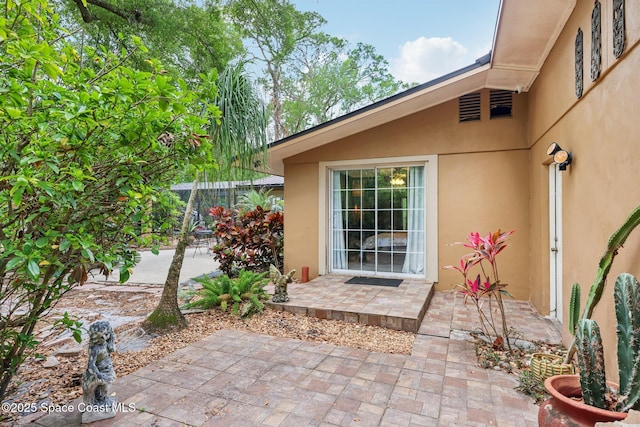 entrance to property featuring a patio and stucco siding