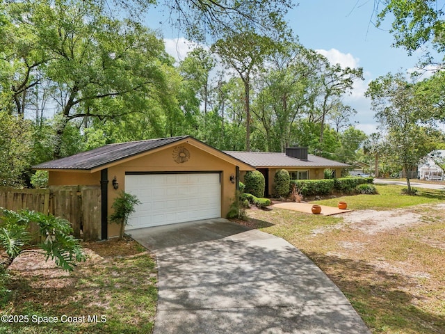 ranch-style house with a garage, stucco siding, metal roof, fence, and driveway