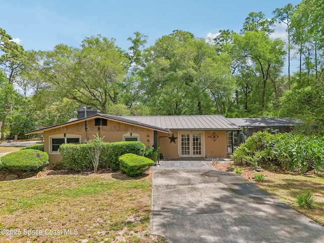 view of front of house with metal roof, french doors, and stucco siding