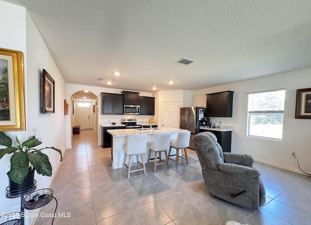 2507 Peralta Dr, Palm Bay, FL 32909 - kitchen featuring an island with sink, arched walkways, visible vents, stainless steel appliances, and baseboards