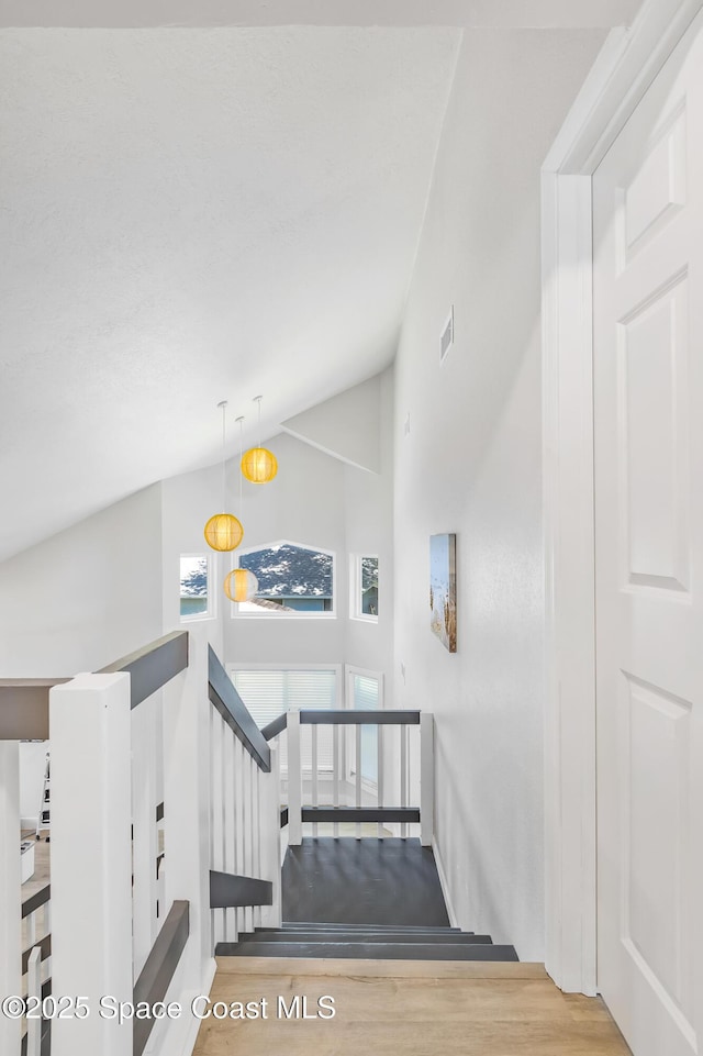 6765 Angeles Rd, Melbourne Beach, FL 32951 - staircase featuring wood finished floors, baseboards, and high vaulted ceiling