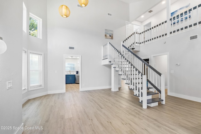 6765 Angeles Rd, Melbourne Beach, FL 32951 - stairs with a towering ceiling, baseboards, plenty of natural light, and wood finished floors