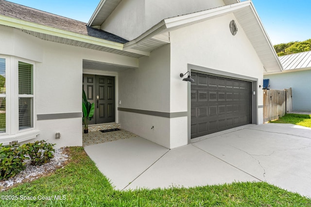 6765 Angeles Rd, Melbourne Beach, FL 32951 - view of exterior entry featuring stucco siding, an attached garage, driveway, a standing seam roof, and metal roof