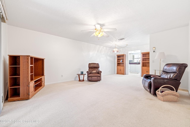 sitting room featuring a ceiling fan, baseboards, and light colored carpet