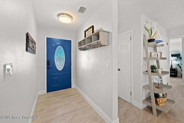 entryway with visible vents, baseboards, and a textured ceiling