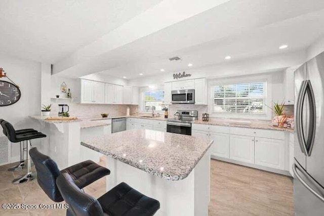 kitchen featuring a breakfast bar area, a healthy amount of sunlight, a sink, and stainless steel appliances