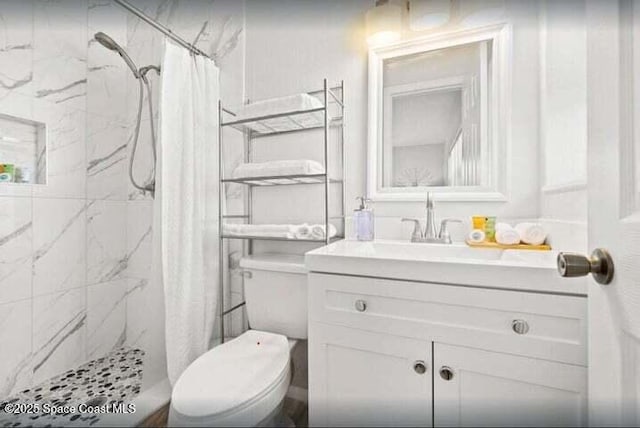bathroom featuring a shower stall, vanity, and toilet