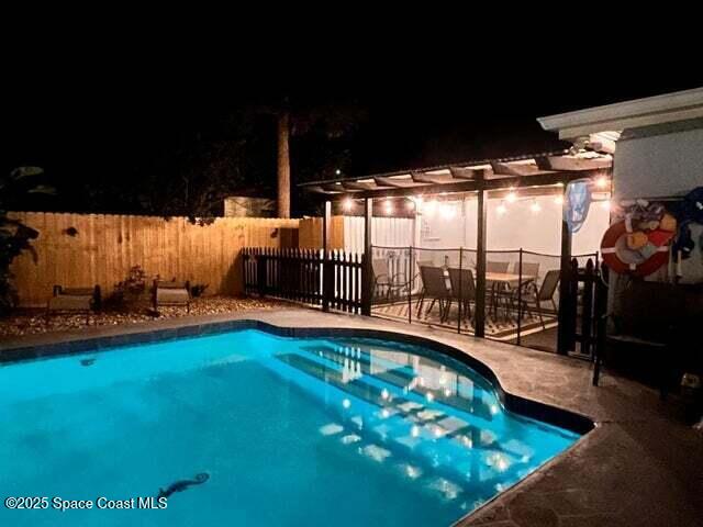 pool at twilight with a fenced in pool, a patio, a pergola, and fence