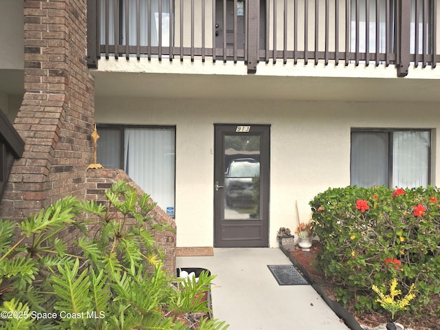 doorway to property featuring stucco siding and a balcony