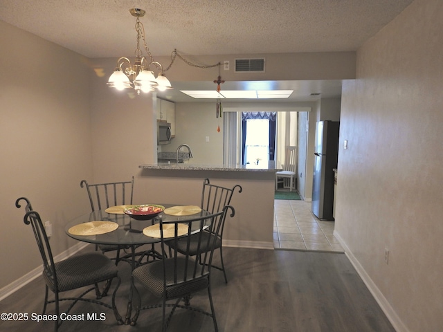 dining room featuring baseboards, a textured ceiling, and visible vents
