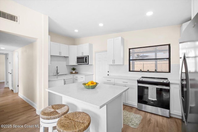 1800 Elmwood Dr, Melbourne, FL 32935 - kitchen featuring a kitchen bar, visible vents, appliances with stainless steel finishes, a sink, and backsplash