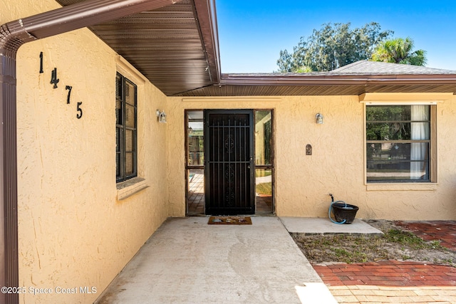 1475 S Oaks Dr, Merritt Island, FL 32952 - doorway to property with stucco siding and a patio area