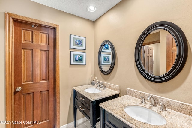 1475 S Oaks Dr, Merritt Island, FL 32952 - bathroom featuring two vanities, tile patterned flooring, a sink, and a textured ceiling