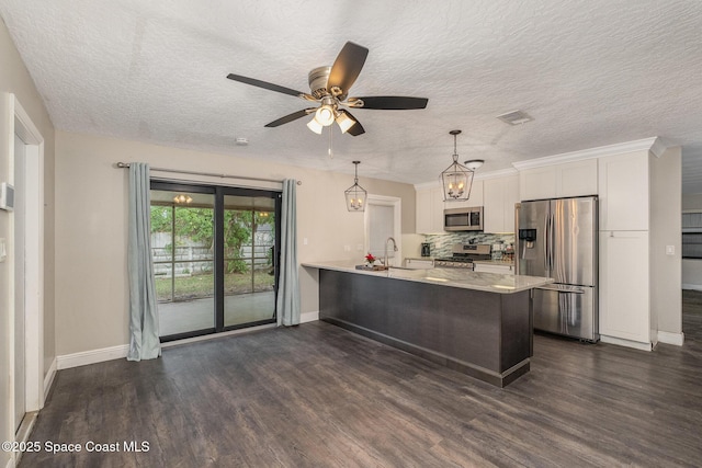 100 Barbados Dr, Merritt Island, FL 32952 - kitchen with light countertops, a sink, a peninsula, appliances with stainless steel finishes, and white cabinetry