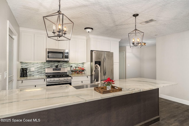 100 Barbados Dr, Merritt Island, FL 32952 - kitchen with stainless steel appliances, a sink, tasteful backsplash, visible vents, and a chandelier