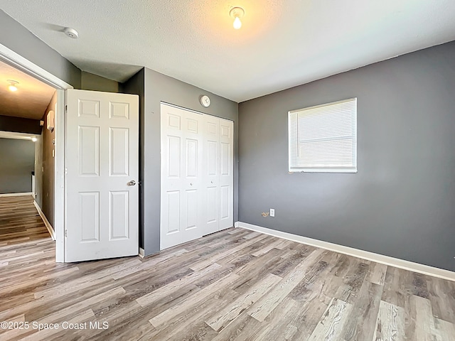 2543 Hathaway Dr, Cocoa, FL 32926 - unfurnished bedroom featuring a closet, light wood-style floors, baseboards, and a textured ceiling