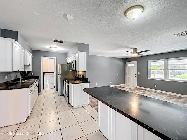 2543 Hathaway Dr, Cocoa, FL 32926 - kitchen with appliances with stainless steel finishes, washer / clothes dryer, a sink, white cabinets, and light tile patterned floors