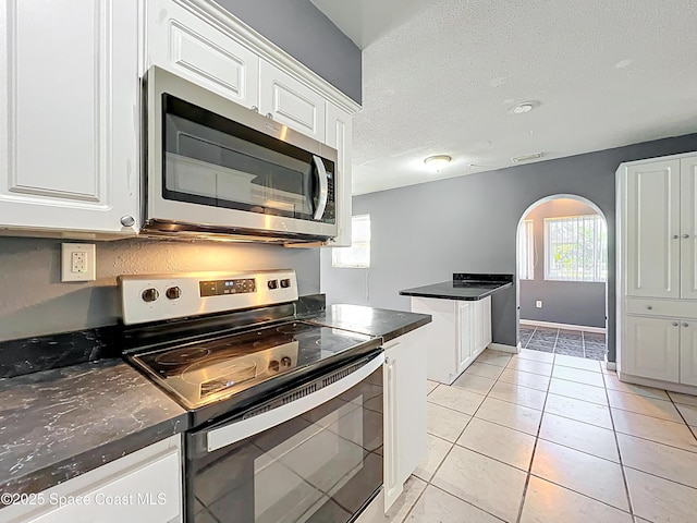 2543 Hathaway Dr, Cocoa, FL 32926 - kitchen featuring appliances with stainless steel finishes, arched walkways, dark countertops, white cabinets, and a textured ceiling