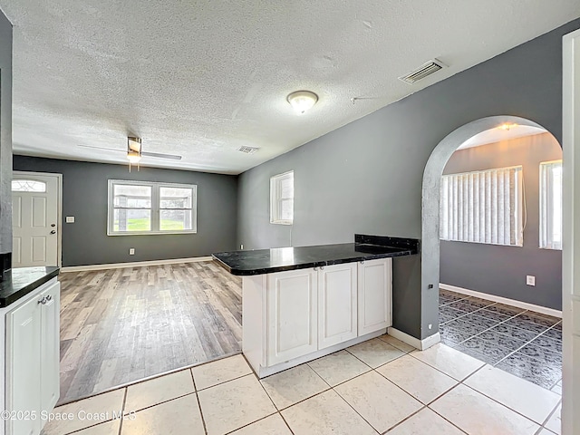 2543 Hathaway Dr, Cocoa, FL 32926 - kitchen with arched walkways, white cabinetry, dark countertops, and a textured ceiling