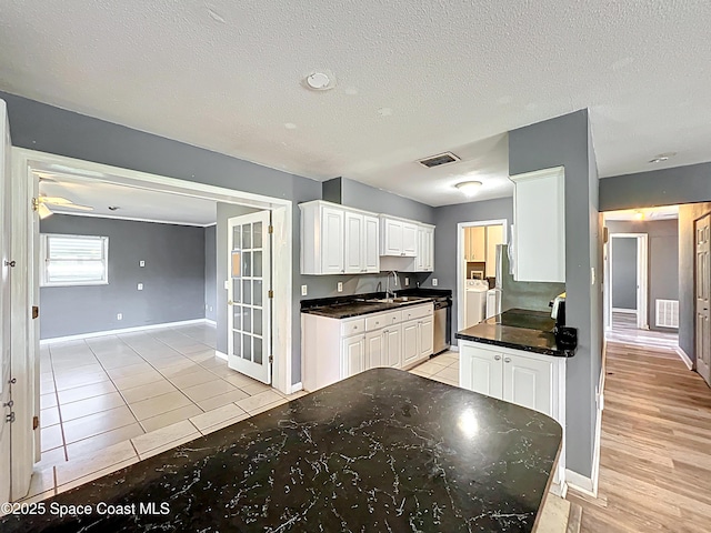 2543 Hathaway Dr, Cocoa, FL 32926 - kitchen featuring white cabinetry, stainless steel dishwasher, baseboards, a sink, and a textured ceiling