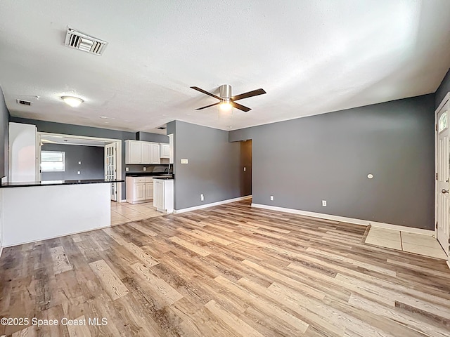 2543 Hathaway Dr, Cocoa, FL 32926 - unfurnished living room with light wood finished floors, a ceiling fan, baseboards, and a textured ceiling