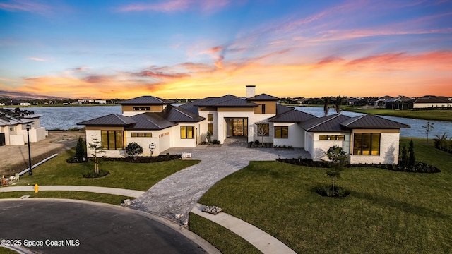 3717 Upper Floridian Way, Rockledge, FL 32955 - prairie-style house with a standing seam roof, metal roof, a lawn, curved driveway, and a water view