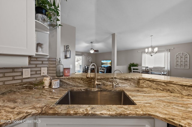 2544 Ventura Cir, Melbourne, FL 32904 - kitchen featuring ceiling fan with notable chandelier, tasteful backsplash, white cabinets, light stone counters, and a sink