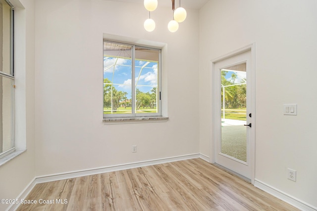unfurnished dining area featuring wood finished floors, baseboards, and a chandelier