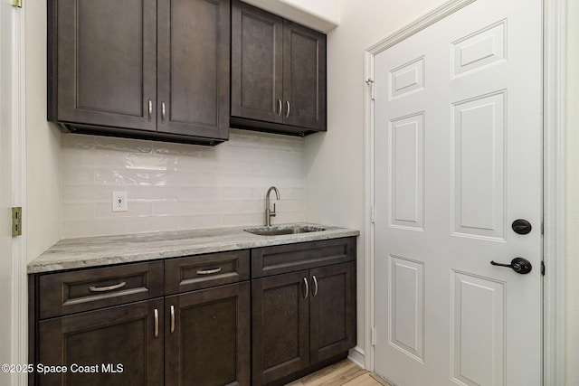 indoor wet bar with decorative backsplash and light wood-type flooring