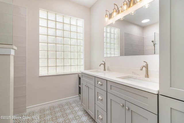 full bath featuring baseboards, a walk in shower, and double vanity