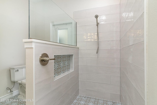 bathroom with tiled shower, toilet, and tile patterned floors