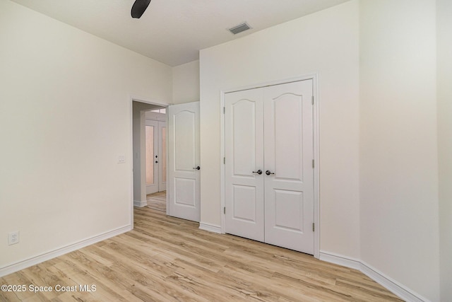 unfurnished bedroom featuring light wood finished floors, baseboards, a closet, and a ceiling fan