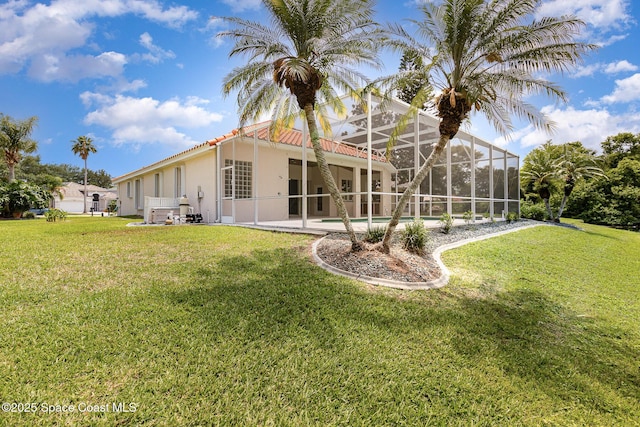 back of house featuring stucco siding, a yard, a tiled roof, a patio area, and a lanai