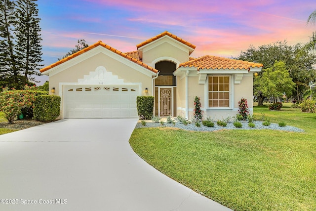 mediterranean / spanish home with a garage, driveway, stucco siding, and a lawn