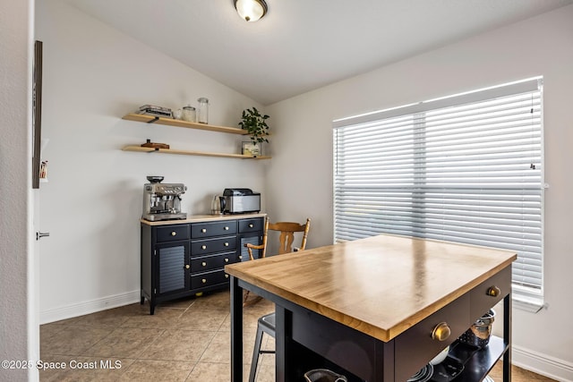 dining space with light tile patterned flooring, vaulted ceiling, and baseboards