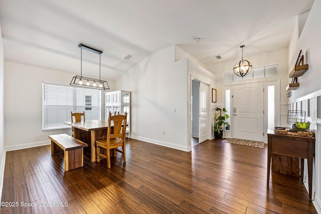 dining room with lofted ceiling, baseboards, a chandelier, and dark wood finished floors