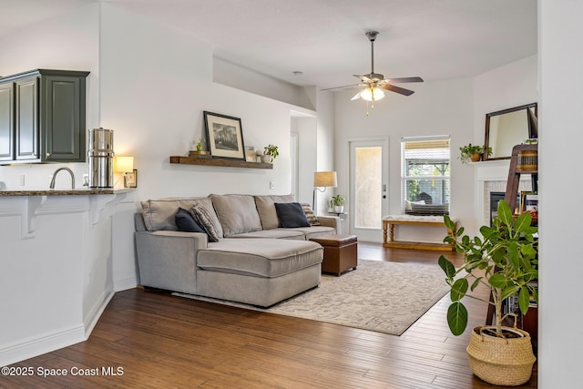 living room with ceiling fan, baseboards, dark wood-style flooring, and a fireplace