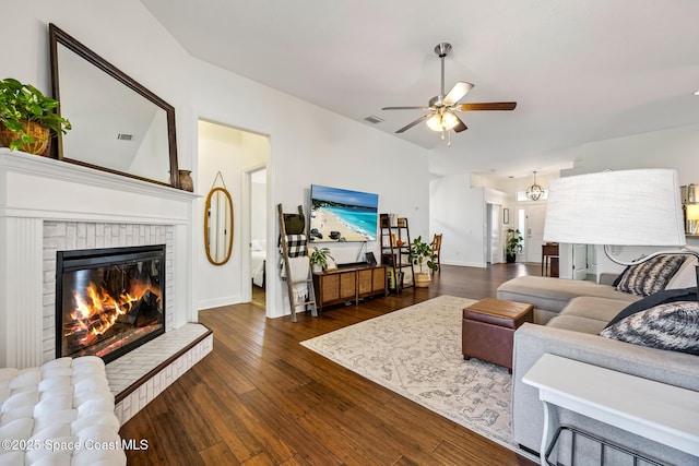 living room with visible vents, a ceiling fan, baseboards, a brick fireplace, and dark wood-style flooring