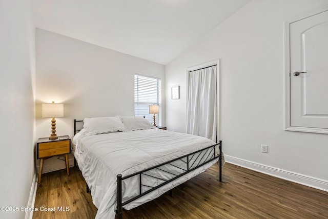 bedroom with vaulted ceiling, baseboards, and wood finished floors