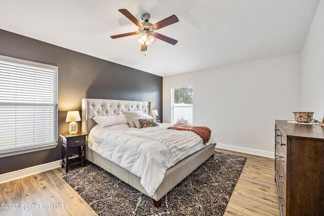 bedroom with lofted ceiling, light wood-style flooring, baseboards, and ceiling fan