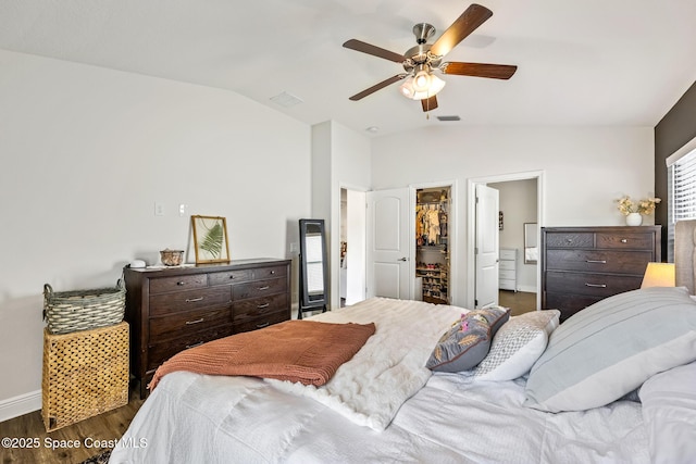 bedroom with a walk in closet, lofted ceiling, wood finished floors, and visible vents