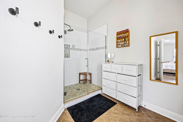 bathroom featuring a shower stall, baseboards, tile patterned flooring, and ensuite bath