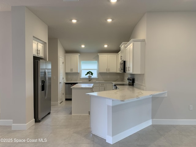 kitchen featuring a peninsula, light stone countertops, recessed lighting, a sink, and stainless steel appliances