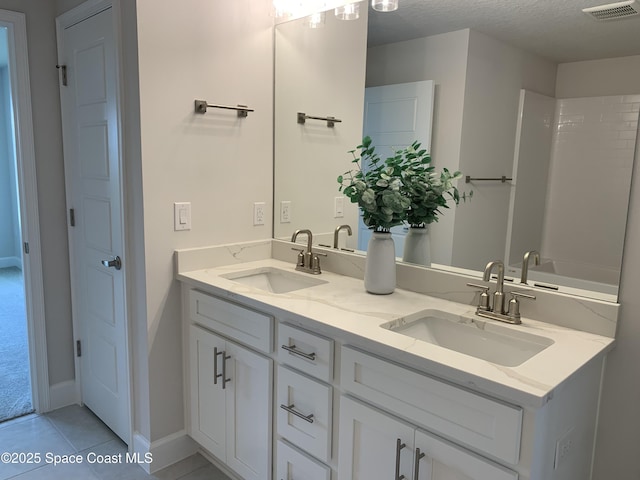 full bathroom featuring double vanity, tile patterned floors, visible vents, and a sink